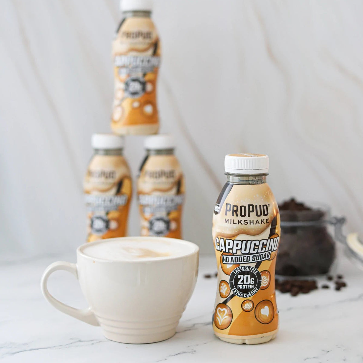 PROPUDDLE Cappuccino bottles on a marble surface with a white mug.